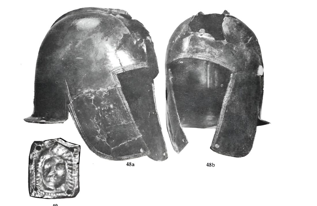 Damaged bronze helmet, maximum height 23.3 cm, sheet thickness 0.1-3 mm, found in May 1969 at the foot of the City Gate, and a gold plate measuring 1.5 x 1.7 cm and weighing 0.900 grams, perforated in all four corners; a thin silver plate with an embossed portrait of a young woman is located underneath.