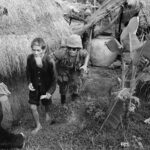 A Marine from 1st Battalion, 3rd Marines, moves a suspected Viet Cong during a search and clear operation held by the battalion 15 miles west of Da Nang Air Base, 1965.